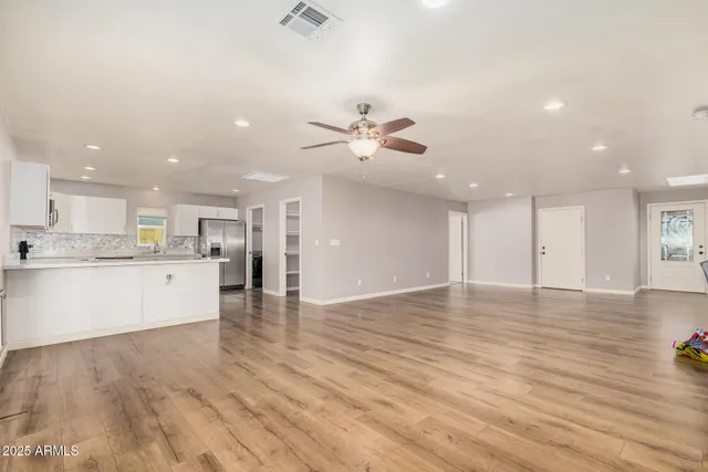 a view of an empty room with kitchen appliances and a ceiling fan
