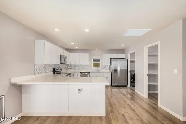 a kitchen with stainless steel appliances kitchen island granite countertop a refrigerator and a sink
