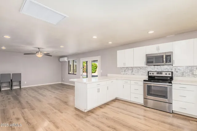 a kitchen with stainless steel appliances granite countertop a stove top oven a sink dishwasher and a refrigerator with wooden floor