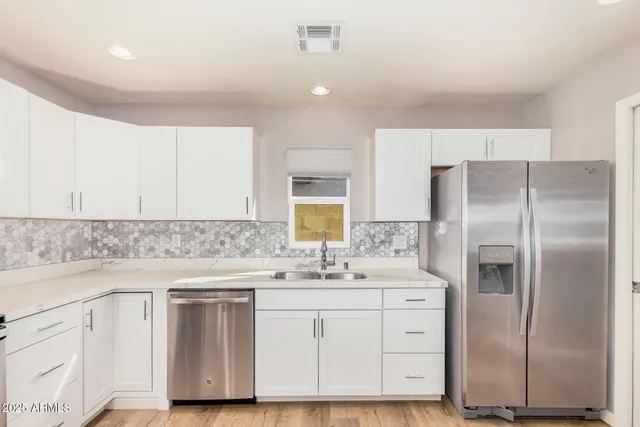 a kitchen with white cabinets and stainless steel appliances