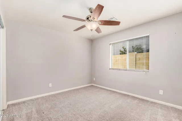 an empty room with a window and a fan