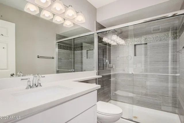 a bathroom with a sink vanity granite toilet and shower