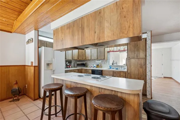 a kitchen with stainless steel appliances kitchen island a table chairs and a refrigerator