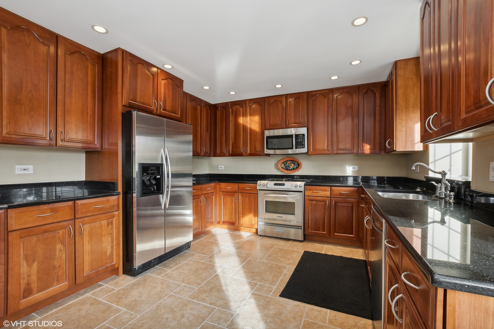 8669 Raintree Lane Orland Park, IL 60462 - Photo 7 of 25 a kitchen with stainless steel appliances granite countertop a refrigerator a stove top oven and sink with wooden cabinets