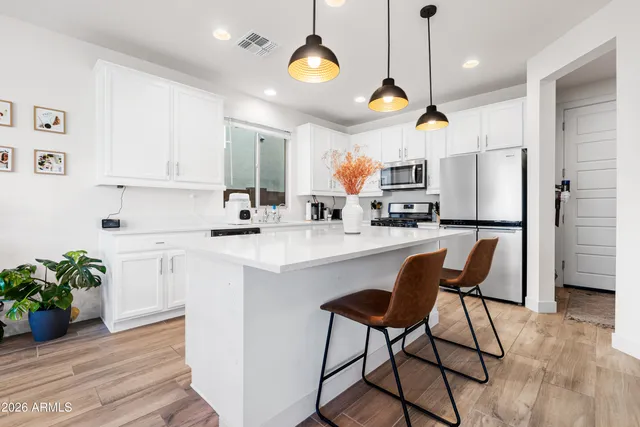 a kitchen with stainless steel appliances granite countertop a refrigerator a oven a sink dishwasher and white cabinets with wooden floor