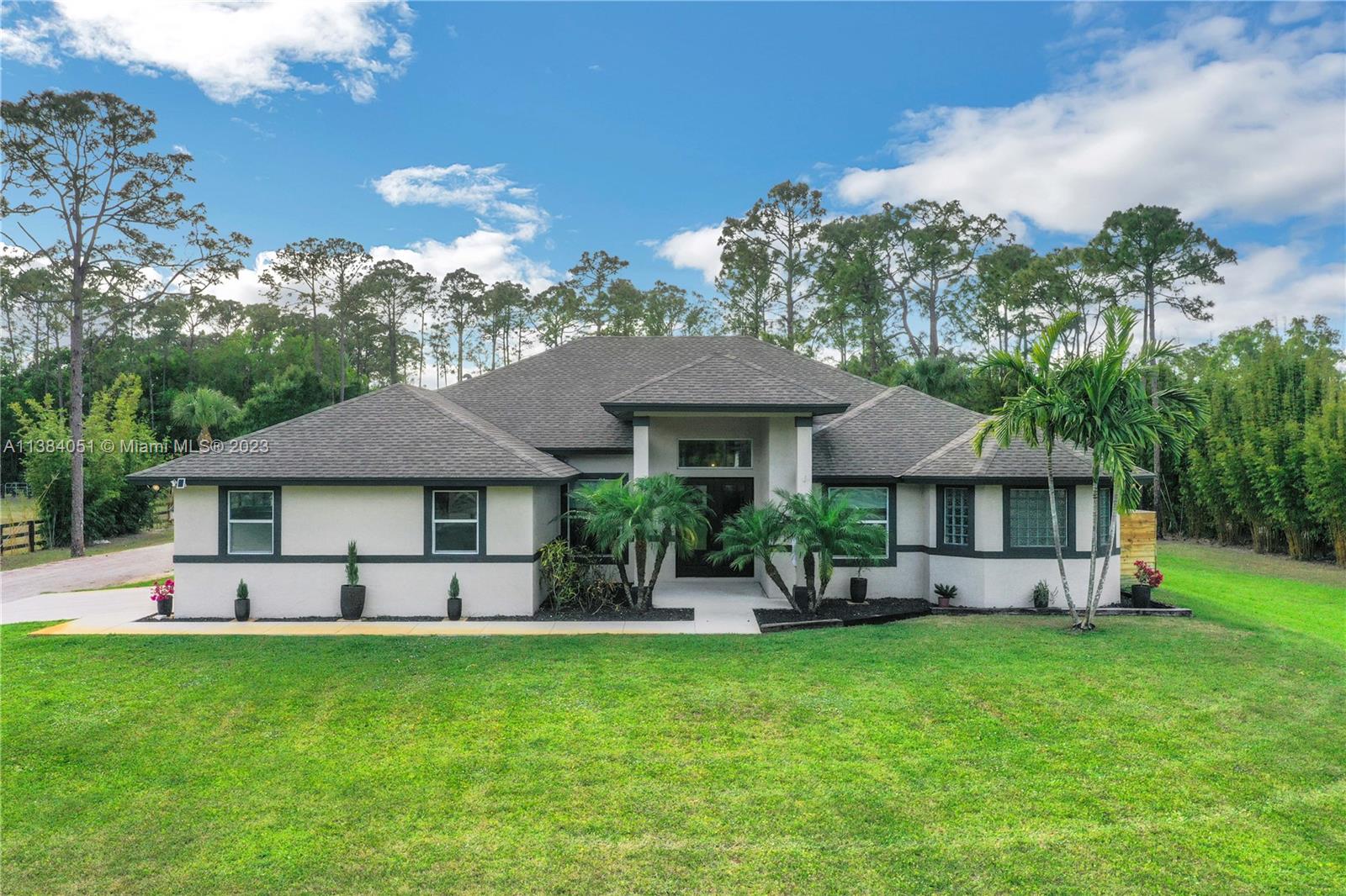 15833 Alexander Run Jupiter, FL 33478 - Photo 1 of 39 a front view of a house with a garden and outdoor seating