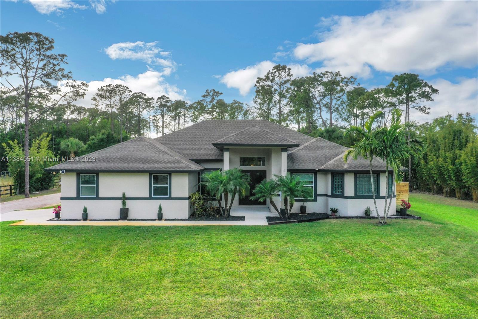 15833 Alexander Run Jupiter, FL 33478 - Photo 29 of 39 a front view of a house with a garden and outdoor seating