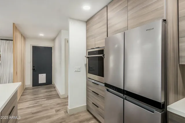 a view of a hallway with stainless steel appliances wooden floor and staircase