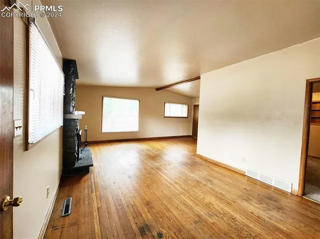 an empty room with wooden floor and windows