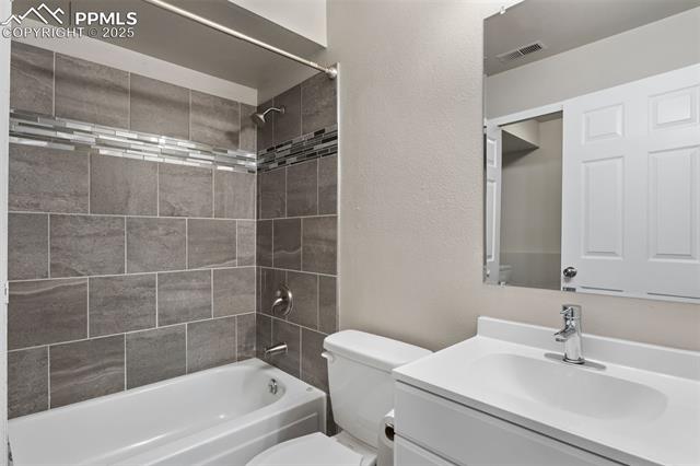 4469 Fenton Road Colorado Springs, CO 80916 - Photo 25 of 38 Bathroom featuring shower / tub combination, vanity, and a textured wall