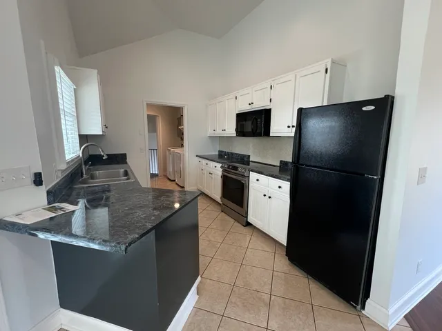 a kitchen with granite countertop a sink a stove and cabinets
