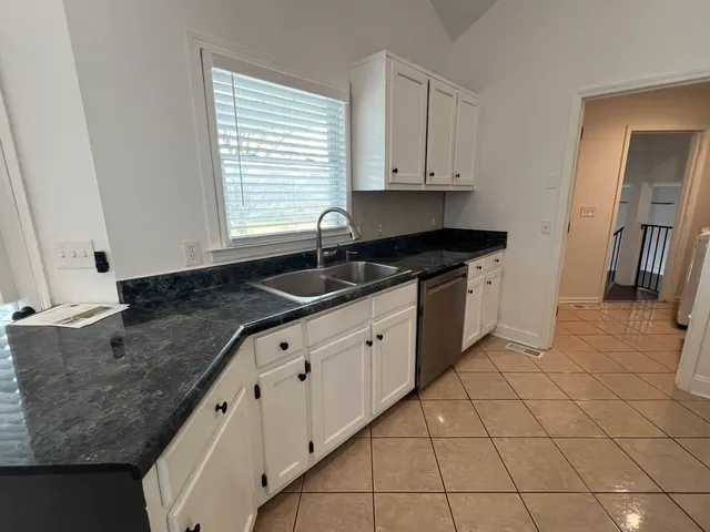 a kitchen with granite countertop white cabinets and stainless steel appliances