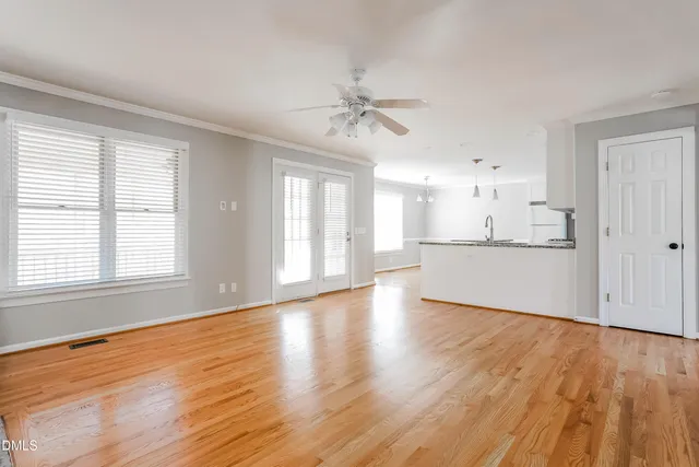 a view of a kitchen and an empty room with wooden floor and a window