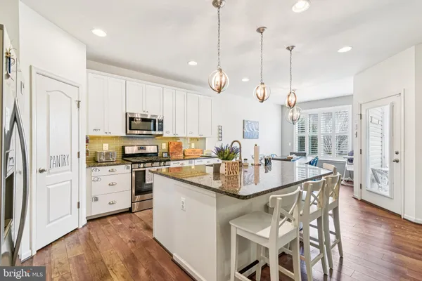 a kitchen with stainless steel appliances granite countertop a sink a stove a refrigerator cabinets and chairs