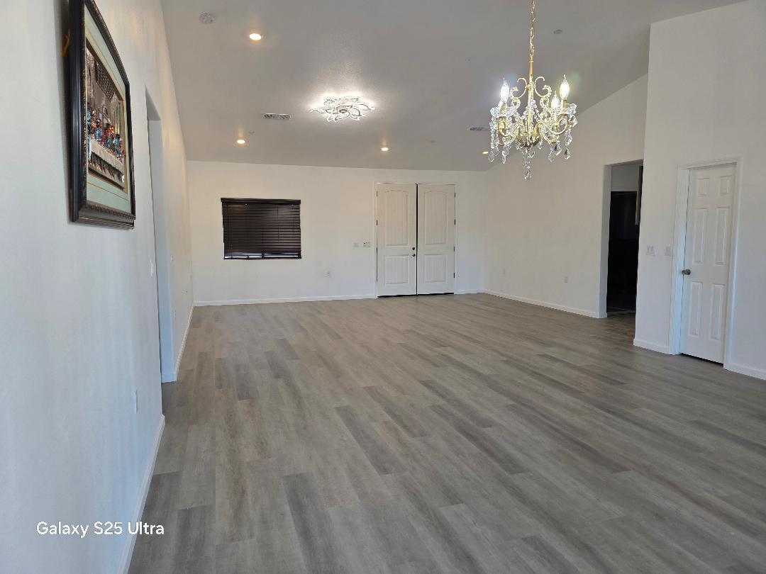 36768 Verde Avenue Madera, CA 93636 - Photo 4 of 17 a view of an empty room with chandelier and wooden floor