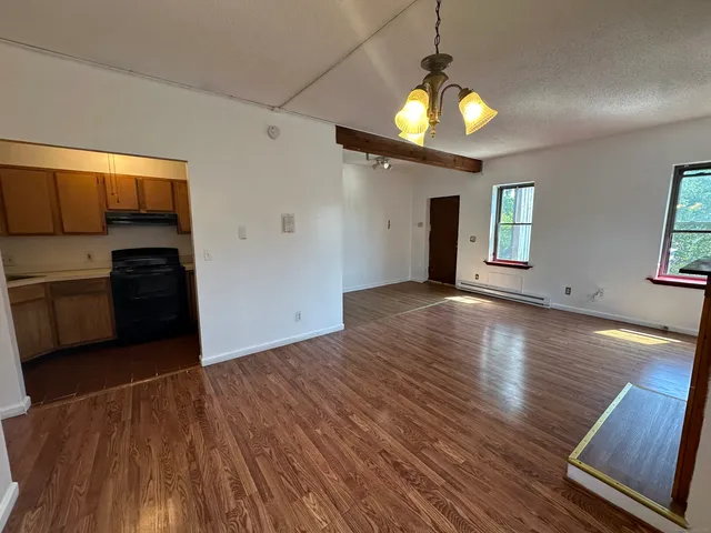 a view of a kitchen with a stove wooden cabinets and a wooden floor