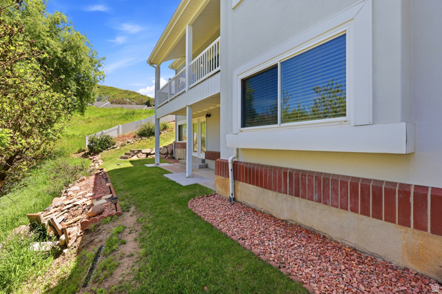 3766 Cardiff Circle Bountiful, UT 84010 - Photo 38 of 46 Exterior featuring a lower-level patio with overhead balcony, red brick foundation, and light stucco siding