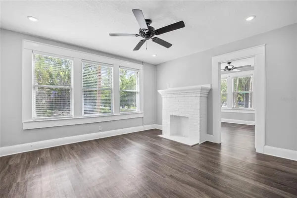 a view of an empty room with a window and wooden floor