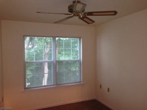an empty room with windows fire place and refrigerator