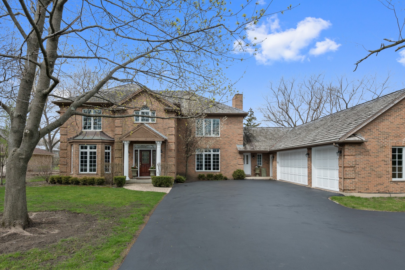 a front view of a house with a garden and trees
