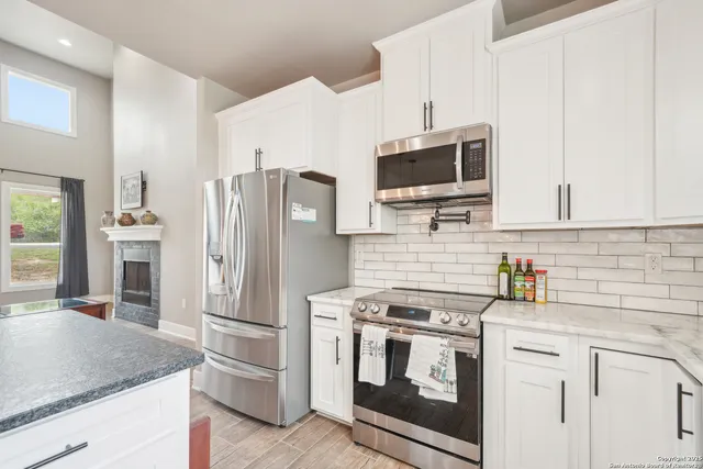 a kitchen with stainless steel appliances white cabinets a sink and a stove