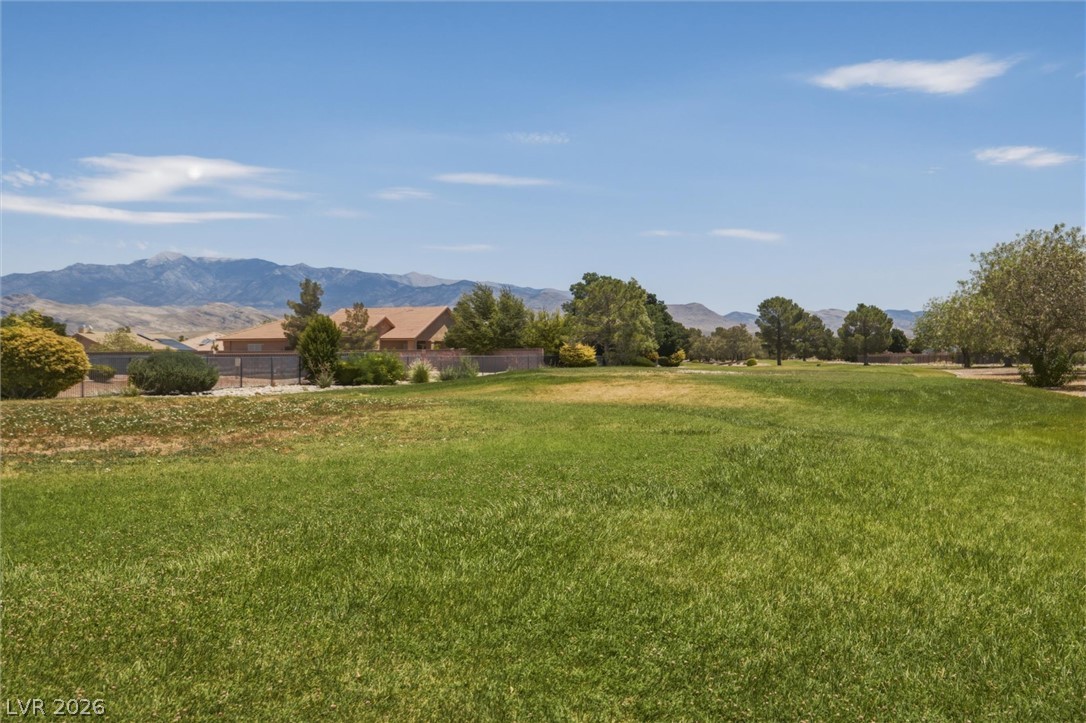 6720 Stubblefield Drive Pahrump, NV 89061 - Photo 47 of 51 Green expanse framed by distant mountains and scattered trees.