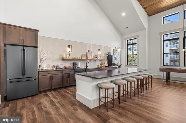 a kitchen with stainless steel appliances granite countertop a refrigerator a stove a sink a dining table and chairs with wooden floor