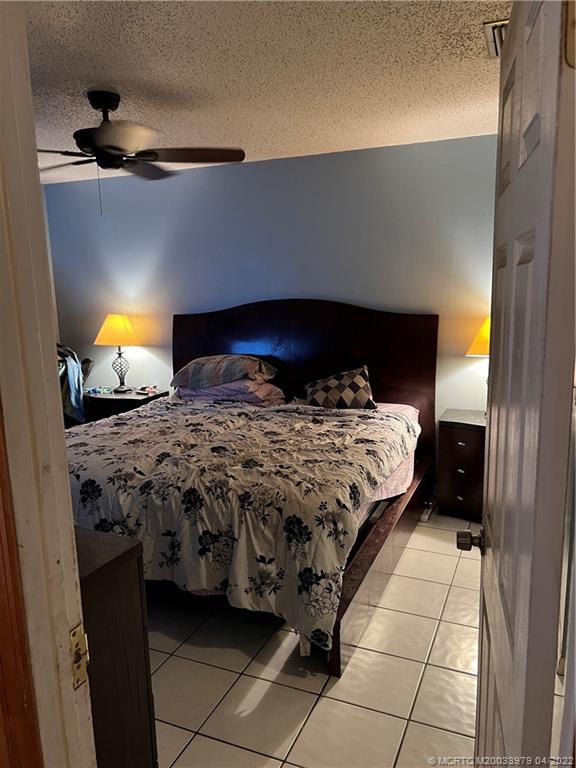 5140 Southeast Dell Street Stuart, FL 34997 - Photo 9 of 21 a bed sitting in a bedroom next to a lamp