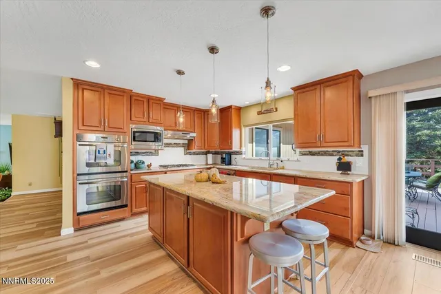 a kitchen with stainless steel appliances granite countertop a refrigerator a sink dishwasher a stove and white countertops with wooden floor