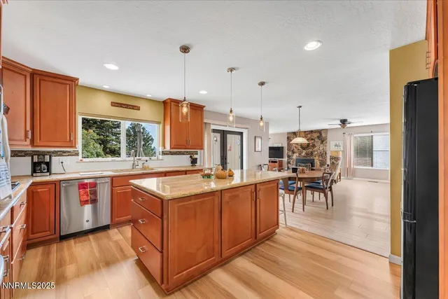 a kitchen with stainless steel appliances granite countertop a stove top oven a sink dishwasher a dining table and chairs with wooden floor