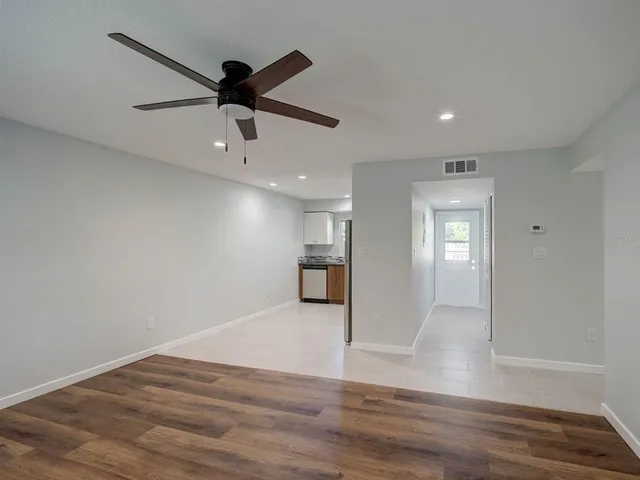 a view of empty room with wooden floor and ceiling fan
