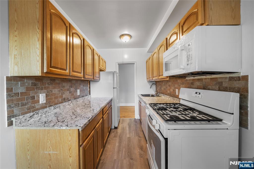 90 Tracey Place, Unit I1 Englewood, NJ 07631 - Photo 7 of 21 a kitchen with granite countertop a sink a stove and refrigerator