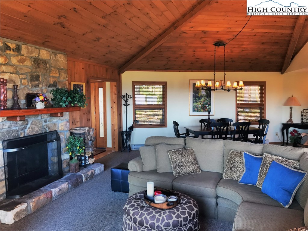 816 Pine Ridge Road Beech Mountain, NC 28604 - Photo 8 of 18 a living room with furniture a fireplace and a floor to ceiling window