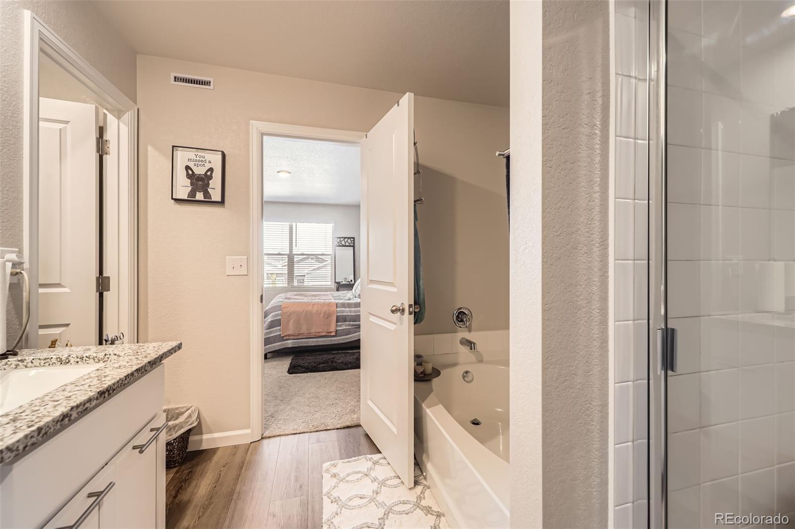 1063 Gianna Avenue Fort Lupton, CO 80621 - Photo 12 of 20 a en suite spacious bathroom with a granite countertop tub shower and a sink
