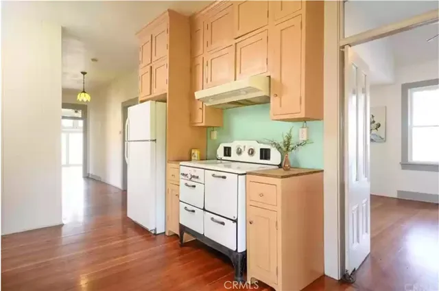 a kitchen with a refrigerator a stove and wooden floor