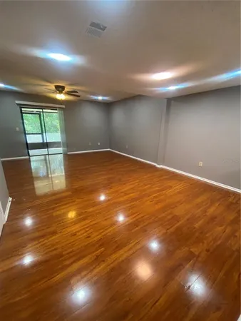 an empty room with wooden floor and windows