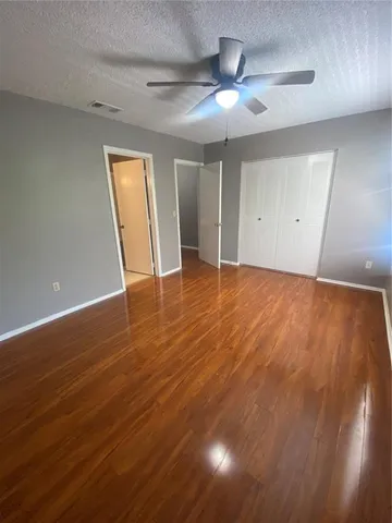 an empty room with wooden floor and fan