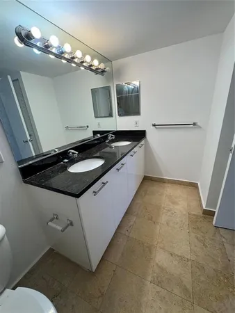 a bathroom with a granite countertop sink a toilet a mirror and vanity