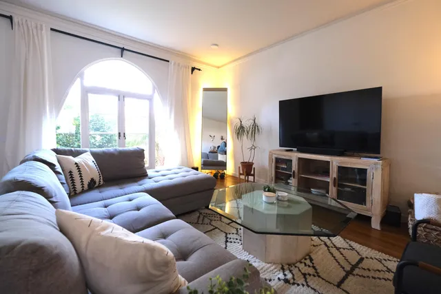 a living room with furniture a flat screen tv and a large window