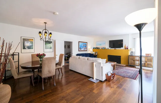 a living room with furniture and a dining table with wooden floor