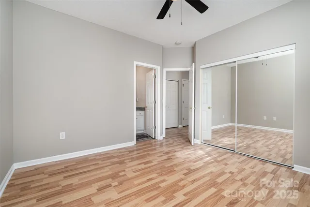 an empty room with ceiling fan and wooden floor