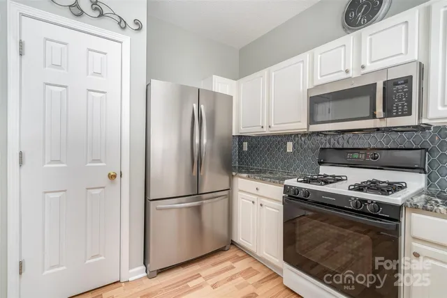 a kitchen with cabinets stainless steel appliances and wooden floor