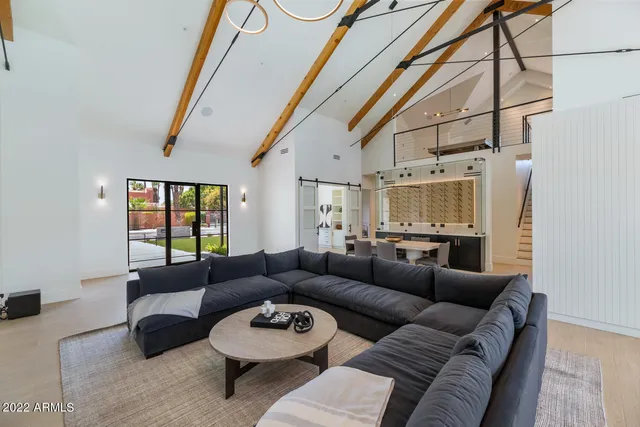 a living room with stainless steel appliances furniture a dining table and a fireplace