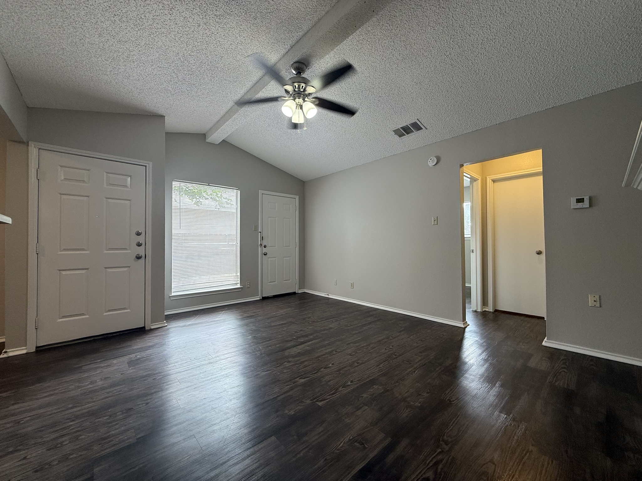 522 Cutty Trail, Unit B Lakeway, TX 78734 - Photo 3 of 20 A spacious room offers vaulted ceilings, sleek dark flooring, and a luminous window.
