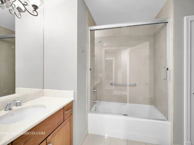 a bathroom with a tub shower sink and mirror