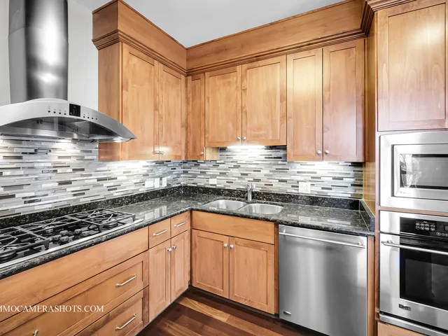 a kitchen with granite countertop a sink stainless steel appliances and cabinets