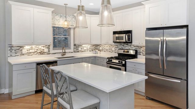 a kitchen with kitchen island a counter top space stainless steel appliances and cabinets