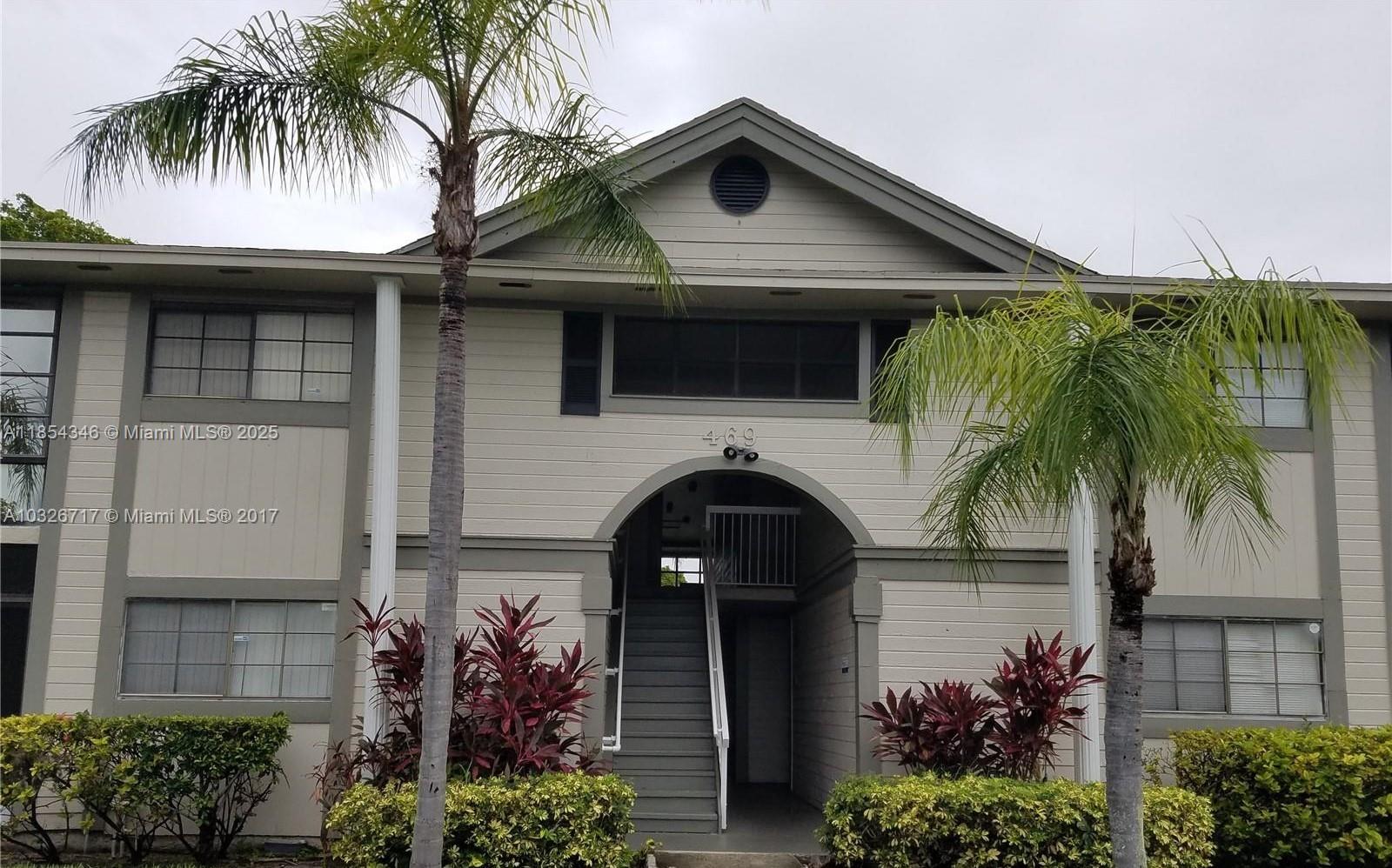 469 Northeast 207th Lane, Unit 207 Miami, FL 33179 - Photo 1 of 25 a front view of a house with a garden