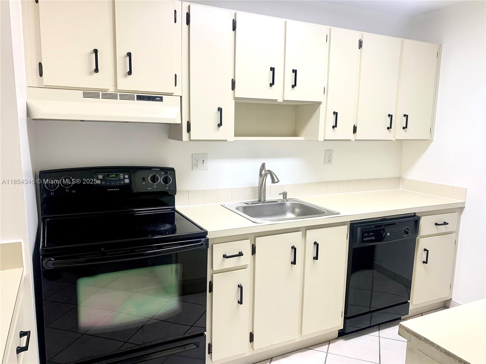 469 Northeast 207th Lane, Unit 207 Miami, FL 33179 - Photo 3 of 25 a kitchen with granite countertop a stove sink and cabinets