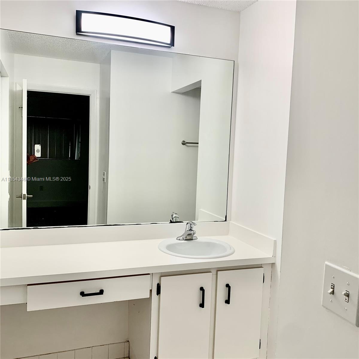 469 Northeast 207th Lane, Unit 207 Miami, FL 33179 - Photo 9 of 25 a bathroom with a sink and a mirror